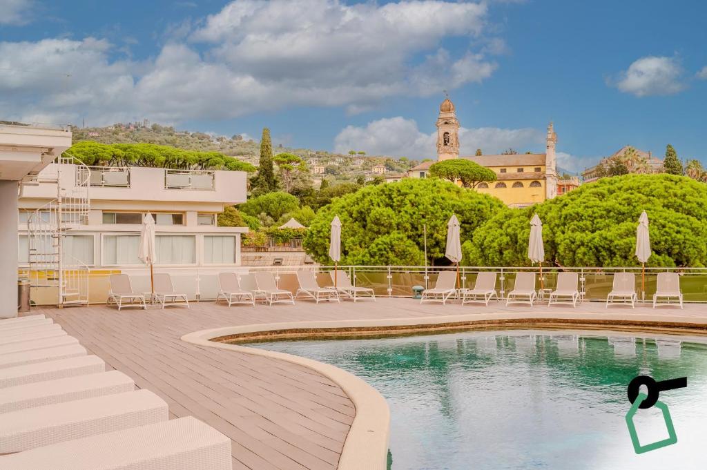 a swimming pool with chairs and a building at Hotiday Santa Margherita Porto in Santa Margherita Ligure