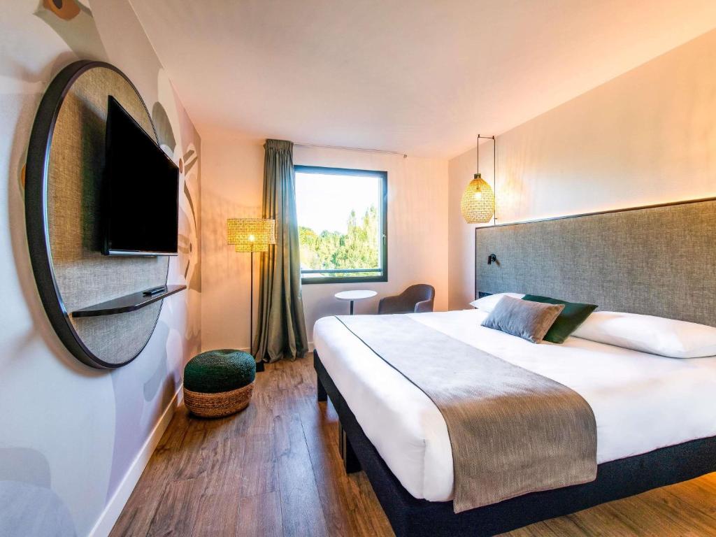 ein Hotelzimmer mit einem großen Bett und einem Spiegel in der Unterkunft ibis Styles Rennes Cesson in Cesson-Sévigné