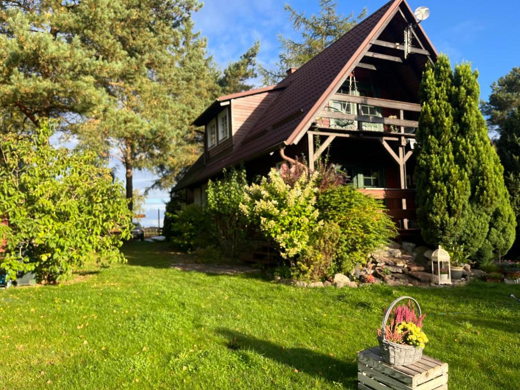 a log house with a porch and a basket of flowers at Dom Zielarki in Żuromino