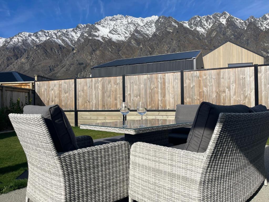 a patio with a table and chairs with mountains in the background at Spa apartment in Queenstown in Queenstown Airport