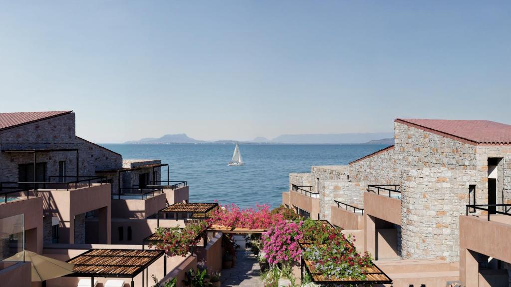 a sailboat in the water between buildings with flowers at Volta Seaside Boutique Hotel in Kokkíni Khánion