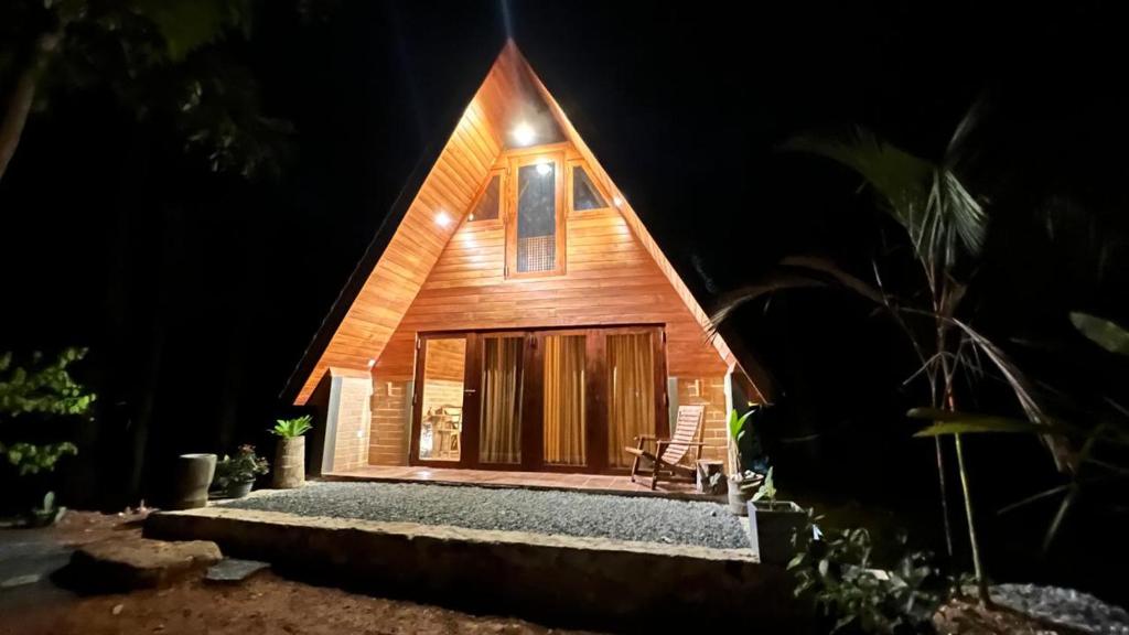 a wooden house at night with a bench in front at Siri Villa Cabana Habaraduwa in Habaraduwa
