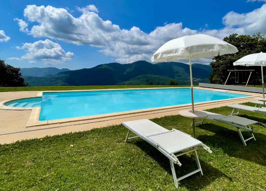 a swimming pool with two lounge chairs and an umbrella at Casa Sperandini in San Marcello Pistoiese