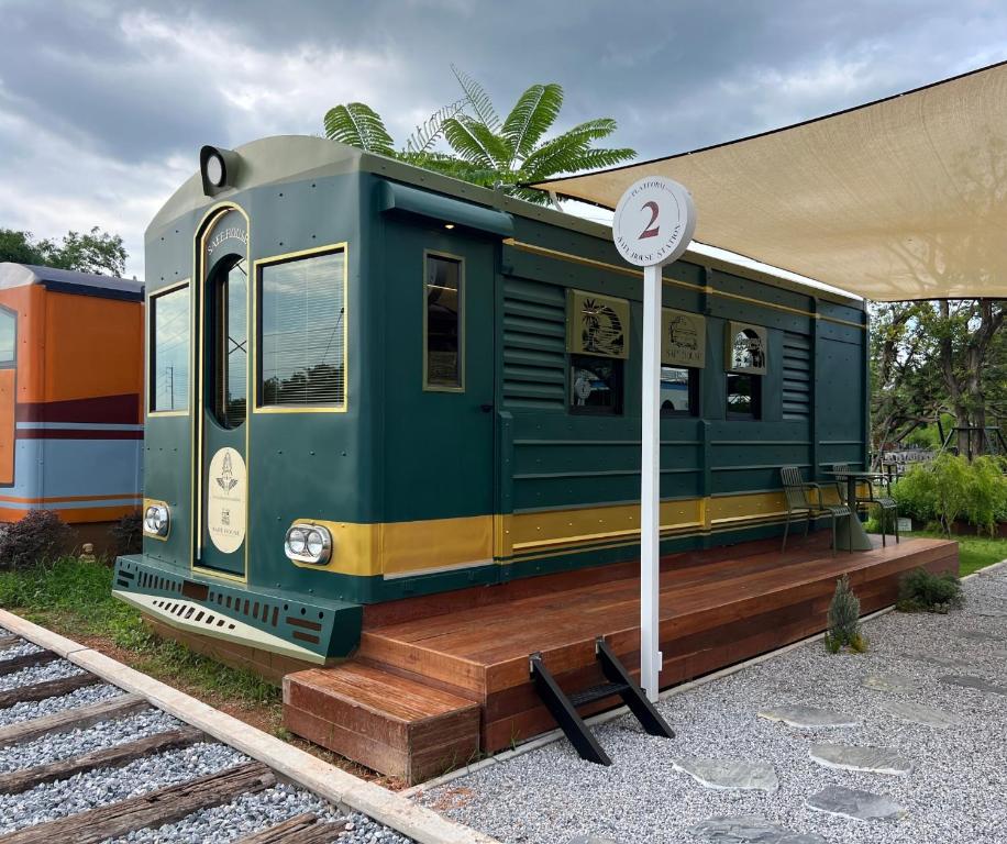 a green train car sitting on tracks next to a sign at SafeHouse resort เซฟเฮ้าท์รีสอร์ท 