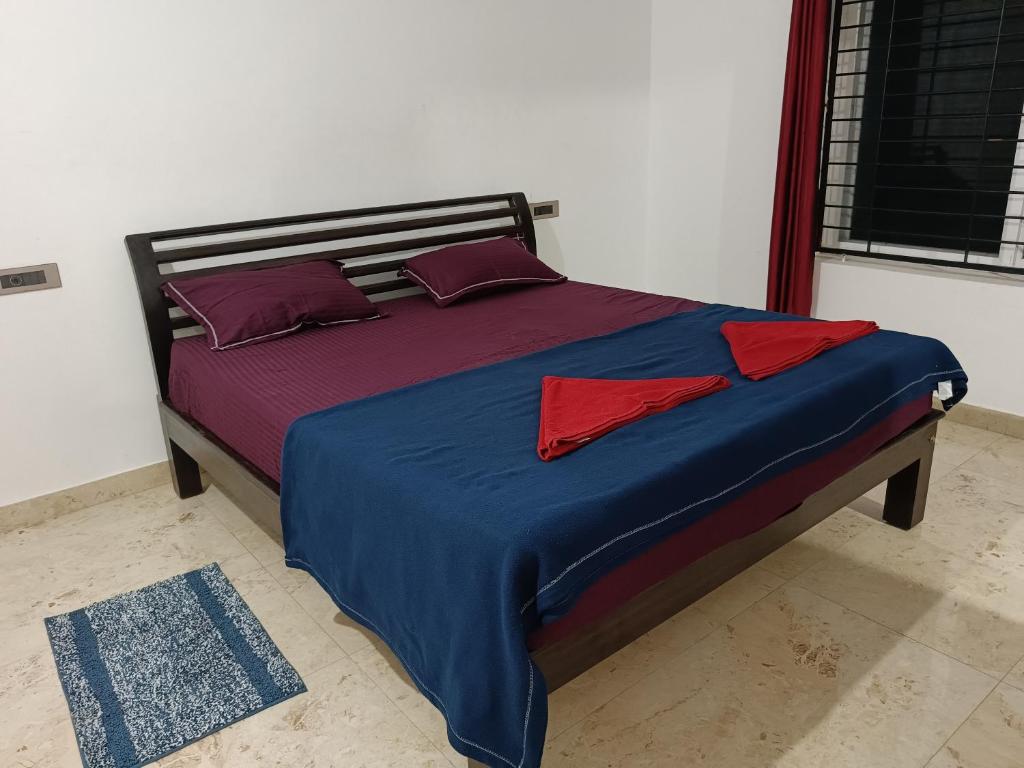 a bed with red pillows and a blue blanket at Fortune Holiday cottage in Madikeri