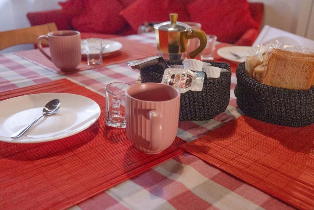 a table with a red and white table cloth with a plate and cups at Casa Roberto in Castelnuovo di Porto