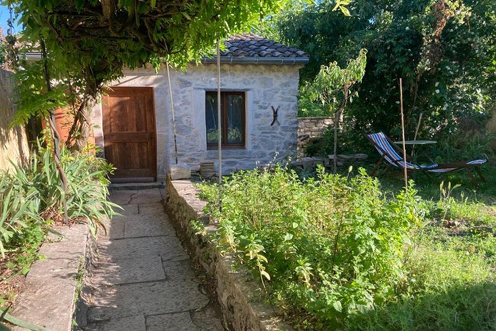 a small stone house with a door in a garden at Un Mazet en famille dans le jardin in Saint-Hippolyte-du-Fort