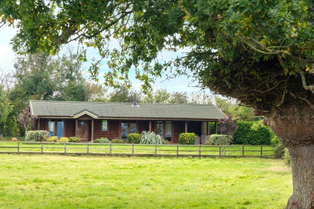 a house in a field with a tree at Alborada in Constable Burton