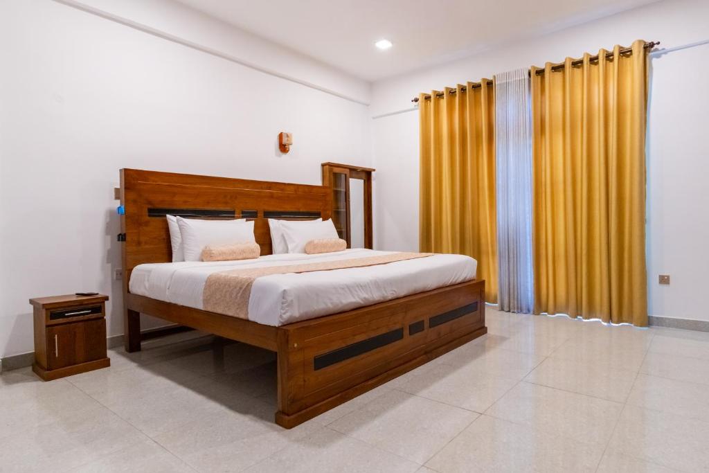 a bedroom with a large wooden bed with yellow curtains at Die ChillOuz Pub & Lodge in Negombo
