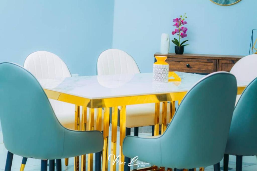 ein Esszimmer mit einem gelben Tisch und blauen Stühlen in der Unterkunft B First Complex in Kolwezi