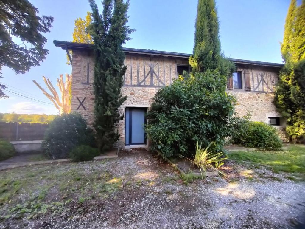 an old brick house with a door in a yard at Appartement dans grange rénovée in Meilhan