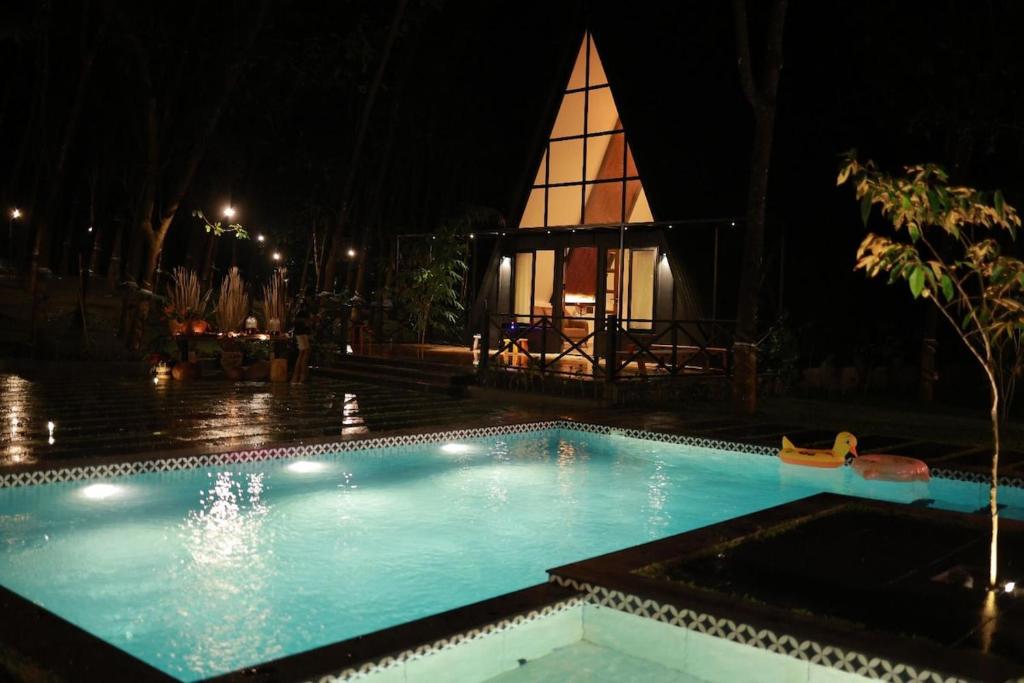 a swimming pool at night with a church in the background at Outhouse by Thottupuram in Muttam