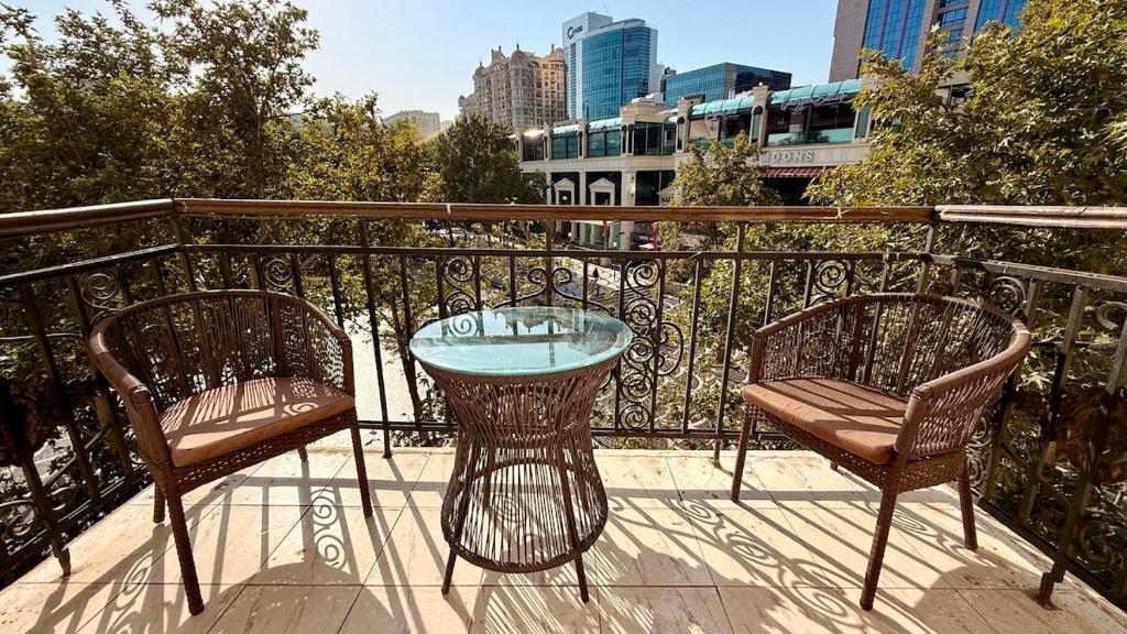 two chairs and a glass table on a balcony at Stylish Stay Overlooking Fountain Square in Baku