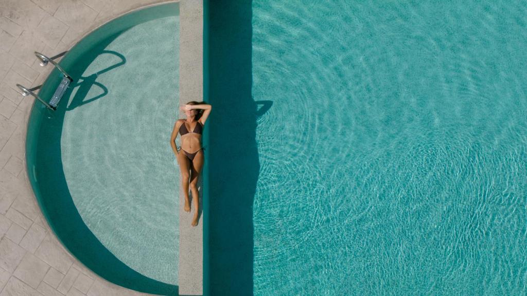 an overhead view of a woman swimming in a swimming pool at Olivia Villa, Celestial haven of luxury, By ThinkVilla in Perama
