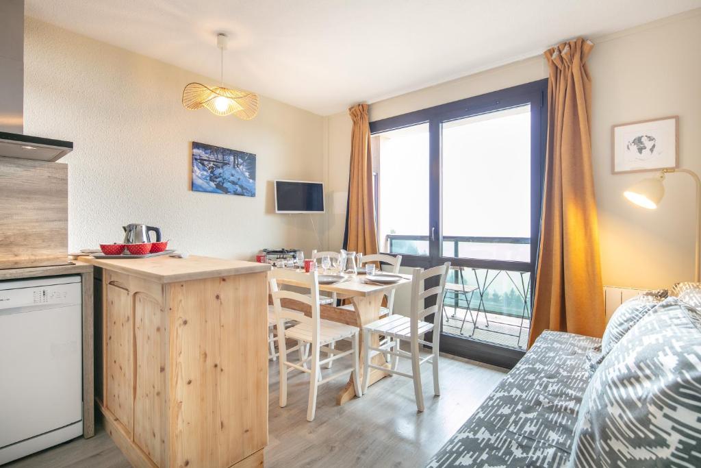 eine Küche und ein Esszimmer mit einem Tisch mit Stühlen und einem Fenster in der Unterkunft L'Alpine Classique - Station de Ski à pied in Chamrousse