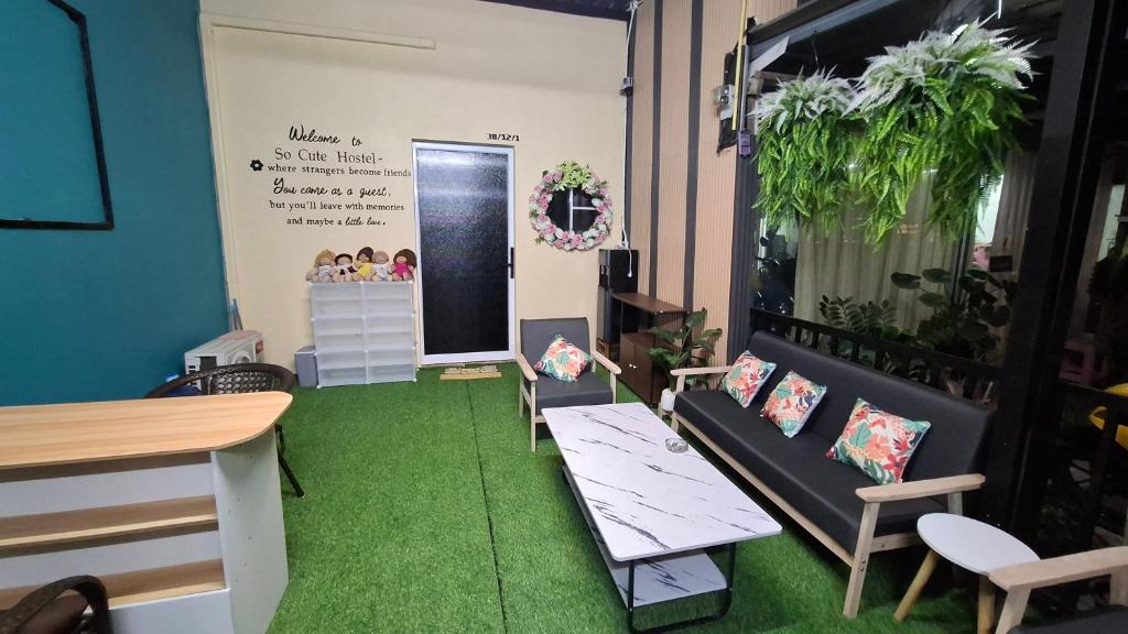 a room with green carpet and a table and chairs at So Cute Hostel, Kai Bae, Koh Chang in Trat