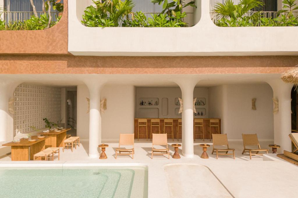 A shallow pool beside a covered patio lined with loungers and a drinks counter.