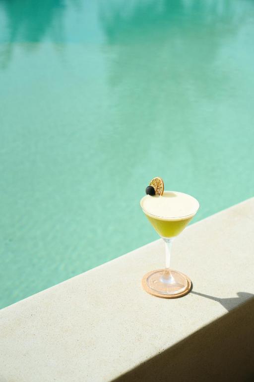 A cocktail set on the sunlit edge of a turquoise pool.