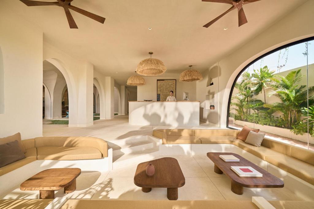 A large tropical lobby lounge with curved sofas, coffee tables, ceiling fans, and a reception desk.