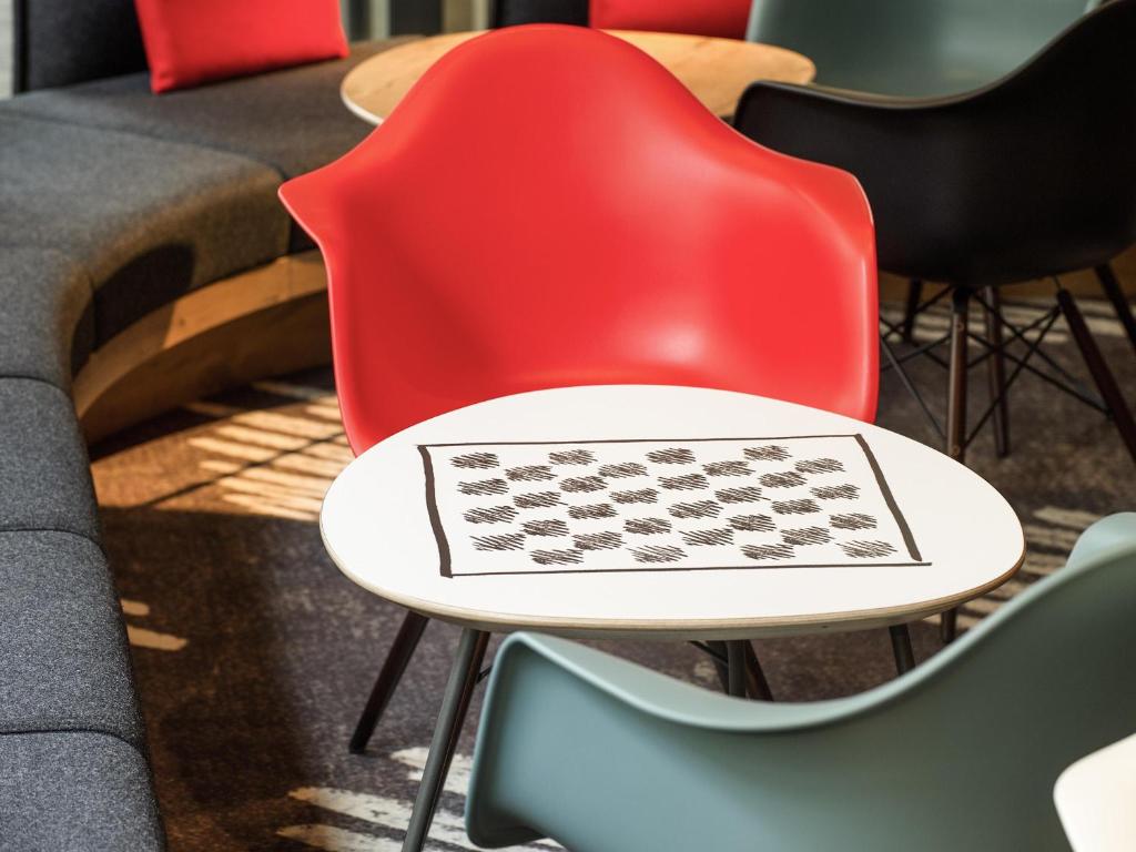 una mesa con una silla roja con un tablero de ajedrez. en ibis Guaiba, en Guaíba