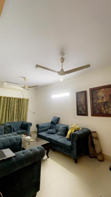 sala de estar con sofás azules y ventilador de techo en Heavens appartment, en Karachi