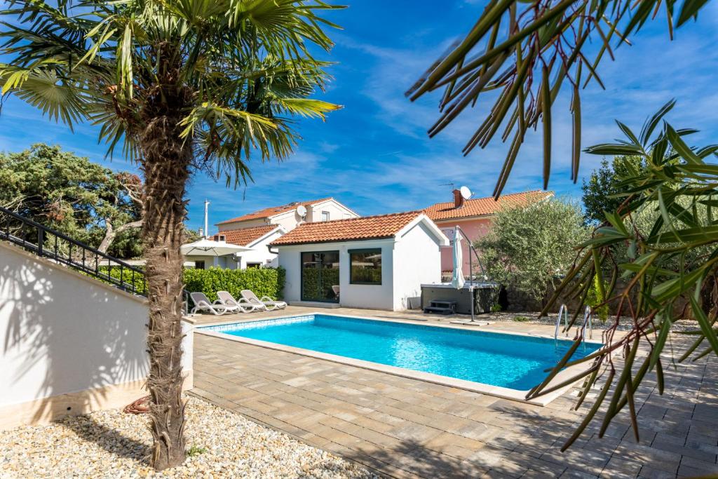 a swimming pool in a backyard with a palm tree at Modern Villa Christian with pool, sauna, and jacuzzi, 10 min walk from the beach in Malinska