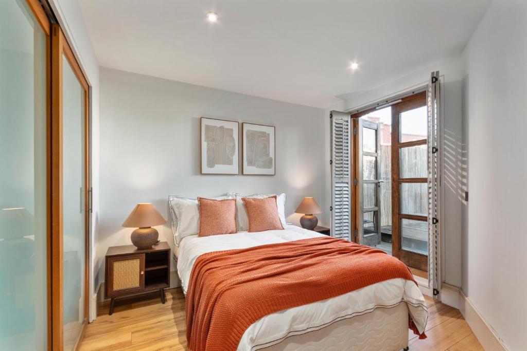 a bedroom with a bed with orange sheets and two lamps at NEW! Fulham 1-bed Apartment with Patio in London