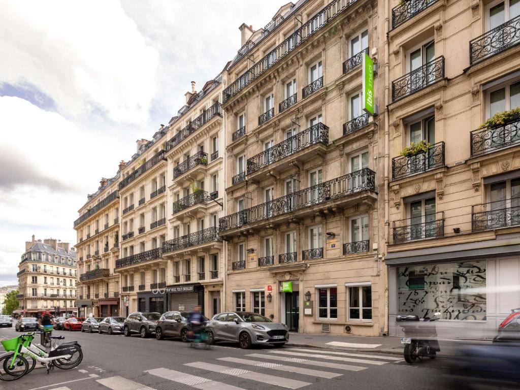 Un gran edificio con coches aparcados delante. en Ibis Styles Paris Gare Saint Lazare, en París
