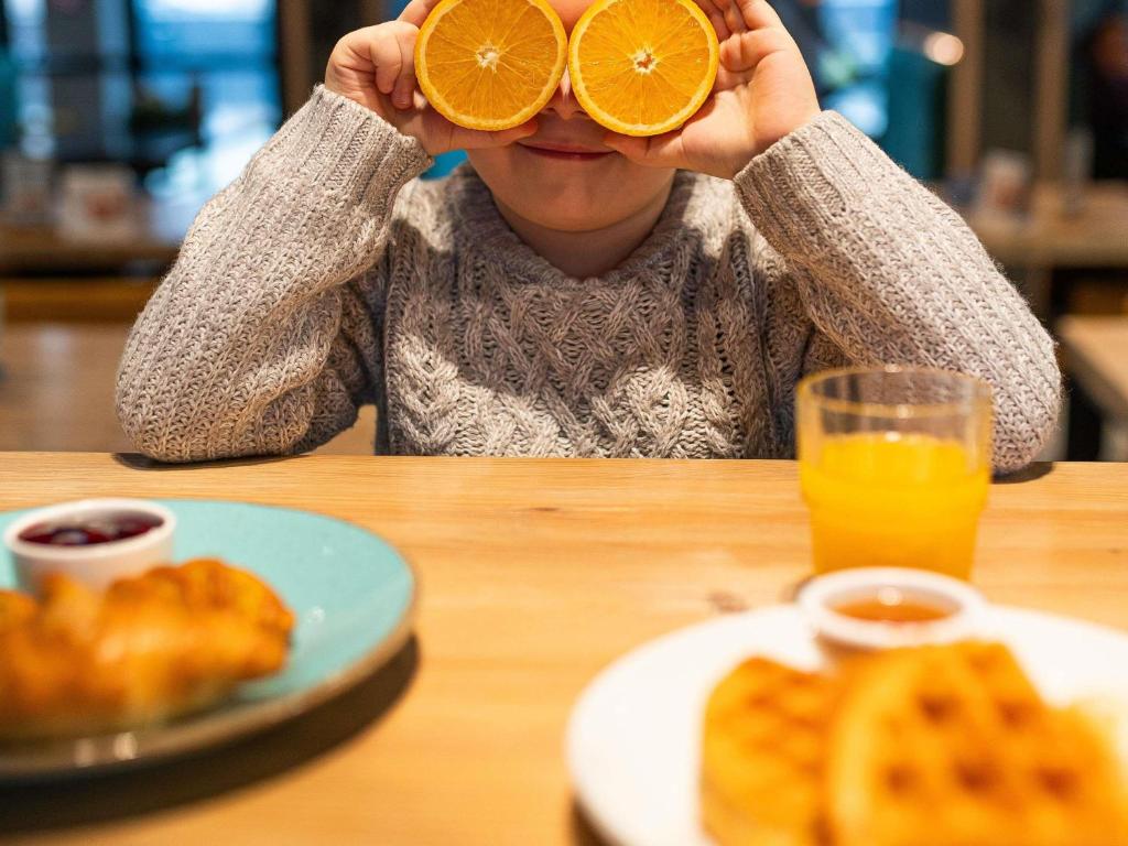 a person sitting at a table with a plate of orange slices at ibis styles Grudziadz in Grudziądz