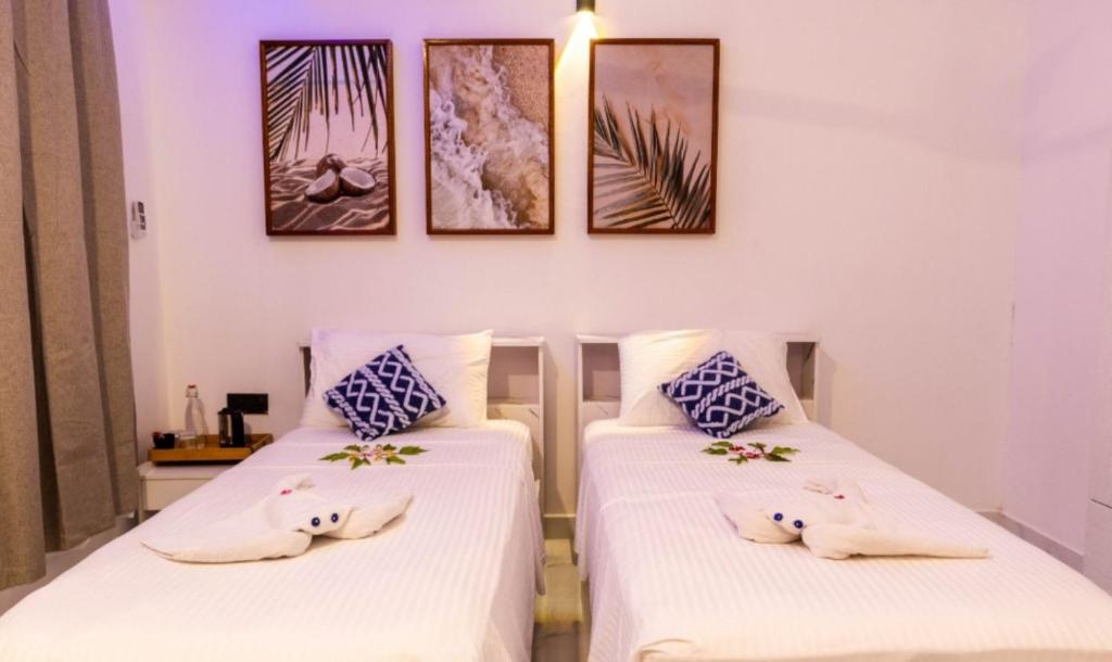 two beds in a room with pictures on the wall at Ocean Sunset in Dhangethi