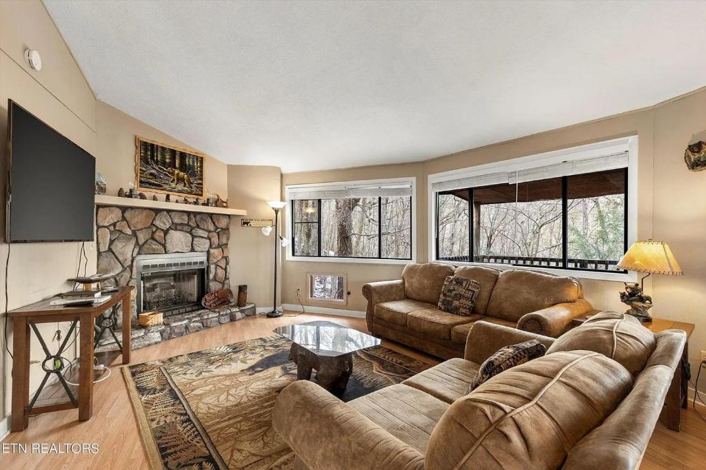 a living room with a couch and a fireplace at Hideaway Chalet - Hot Tub in the Treetops, Arcade Games, + Close to Ober Mountain! in Chalet Village