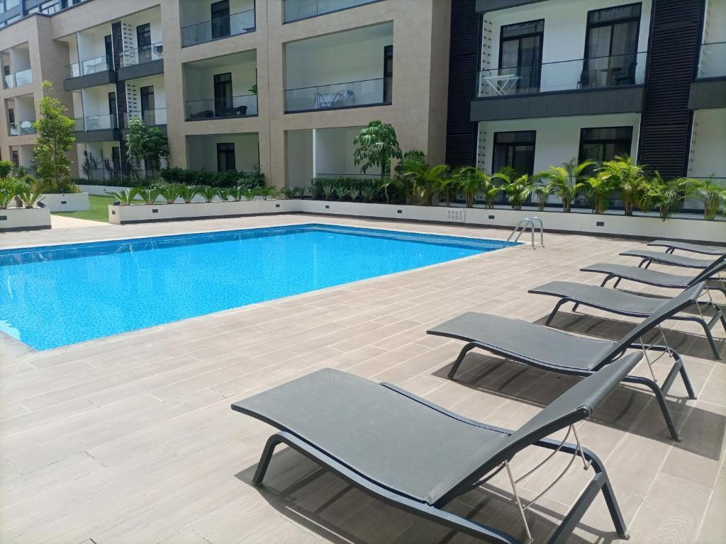 une piscine avec des chaises longues à côté d'un bâtiment dans l'établissement Embassy Gardens Luxury Suites, à Accra