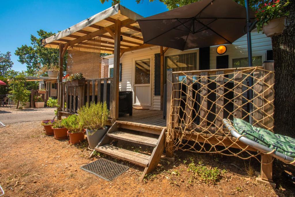 una casa con portico in legno e ombrellone di Marinière a Sainte-Croix-de-Verdon