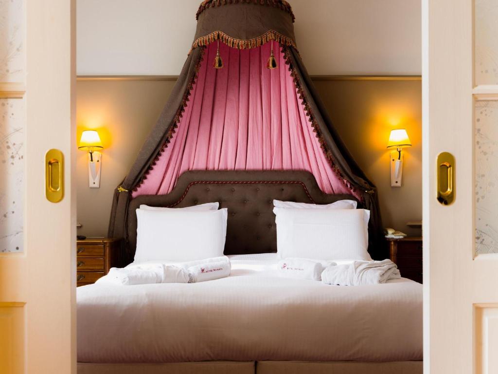 a bedroom with a bed with a pink canopy at Mercure Moulins Centre Hôtel de Paris in Moulins
