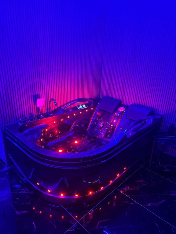 fioletowy pokój z wanną z oświetleniem w obiekcie Love & Jacuzzi w Bukareszcie