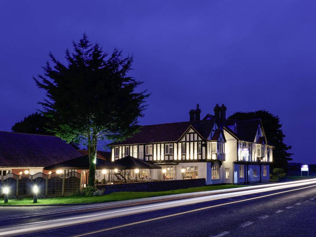 a large house with lights on a street at night at Mercure Thame Lambert Hotel in Chinnor