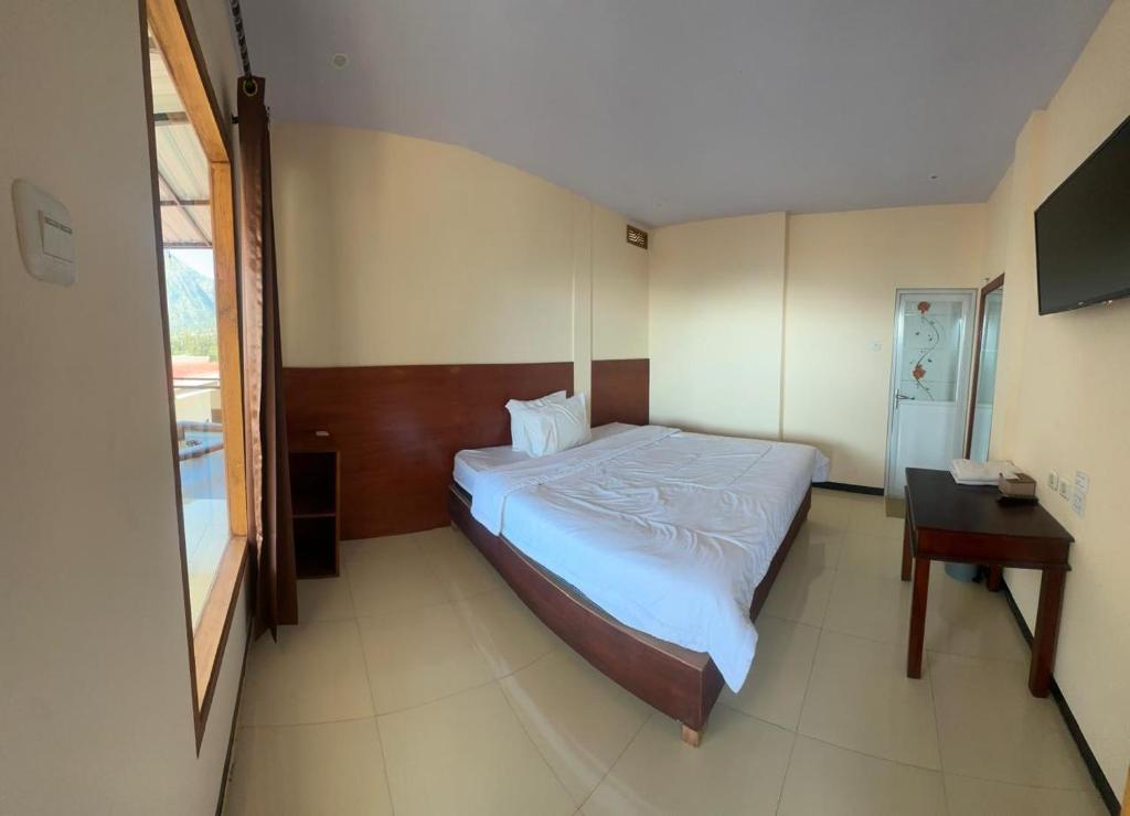 een slaapkamer met een bed en een bureau erin bij PESONA BROMO Homestay in Probolinggo