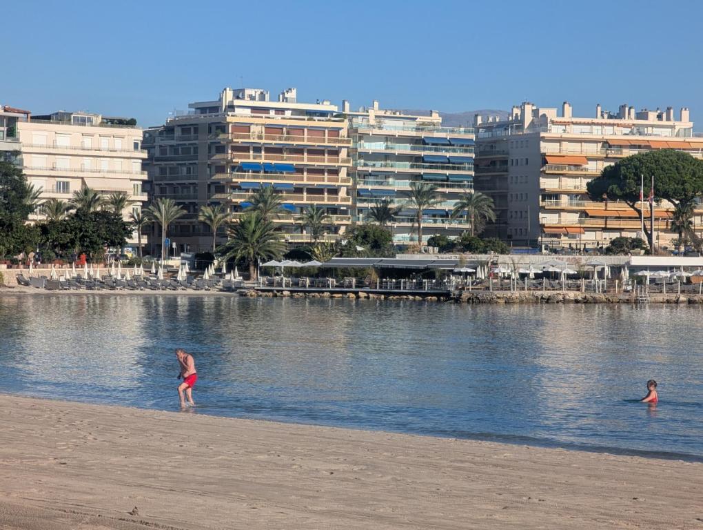 two people in the water on a beach with buildings at Luxury studio next to beaches and old town Antibes in Antibes