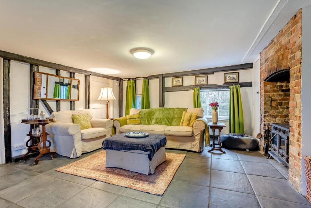 een woonkamer met een bank en een open haard bij Boldshaves Cottage in Woodchurch
