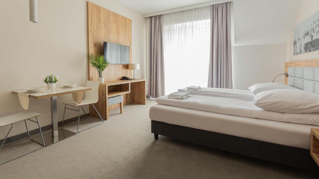 a bedroom with a bed and a desk and a table at VacationClub - Aparthotel Czarna Góra, Apartament 339 in Sienna