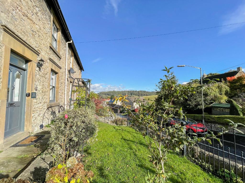 a house with a grass yard next to a building at Skye House in Bakewell