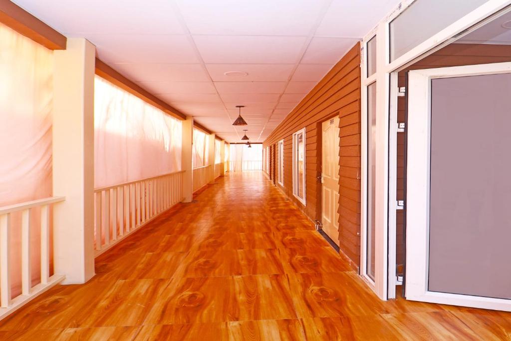an empty hallway of a building with wood floors and a window at Hotel O Gala Banquet in Rānchī