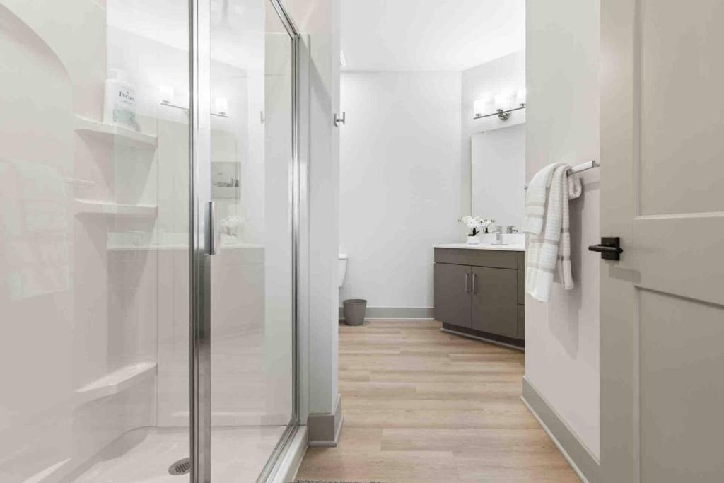 Wilders GroveにあるSerenity Living 5 Min From Downtownのガラスのシャワーと洗面台を備えたバスルーム