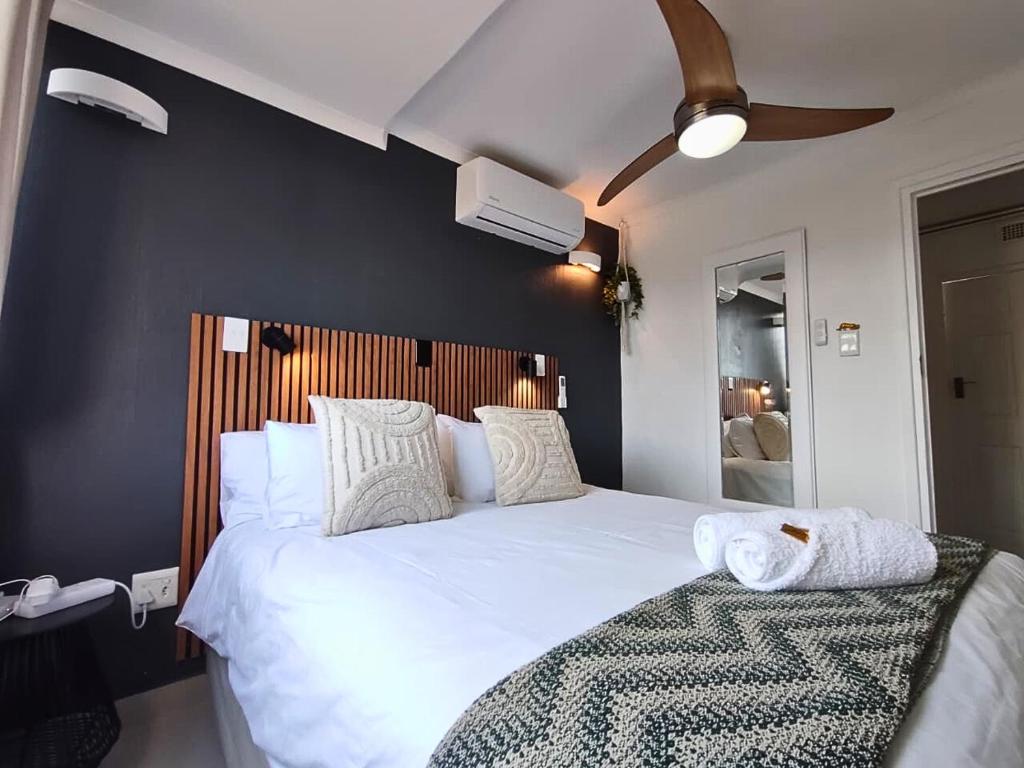 a bedroom with a large white bed and a ceiling fan at Cosy Beach Cottage 52 Chaka's Rock Chalets Resort in Ballito
