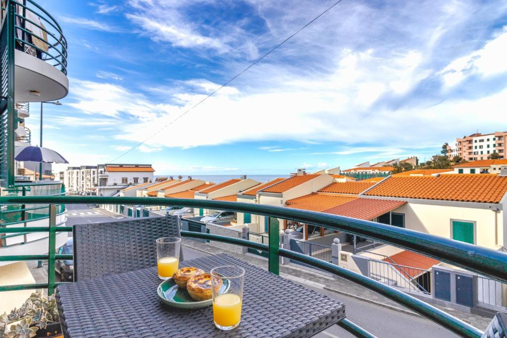 a table with a plate of food on a balcony with orange juice at Carmo Lookout in Câmara de Lobos