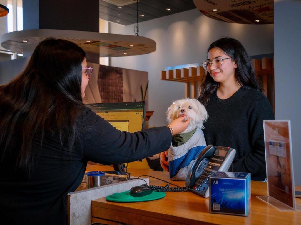 two women standing at a counter with a dog at ibis Copiapo in Copiapó