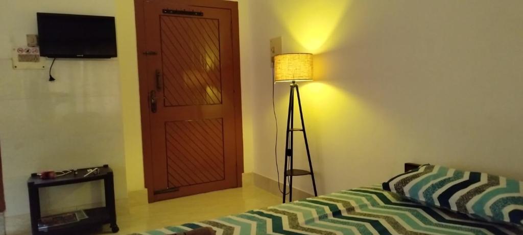 a room with a bed and a lamp and a door at Ade's Homestay in Guwahati