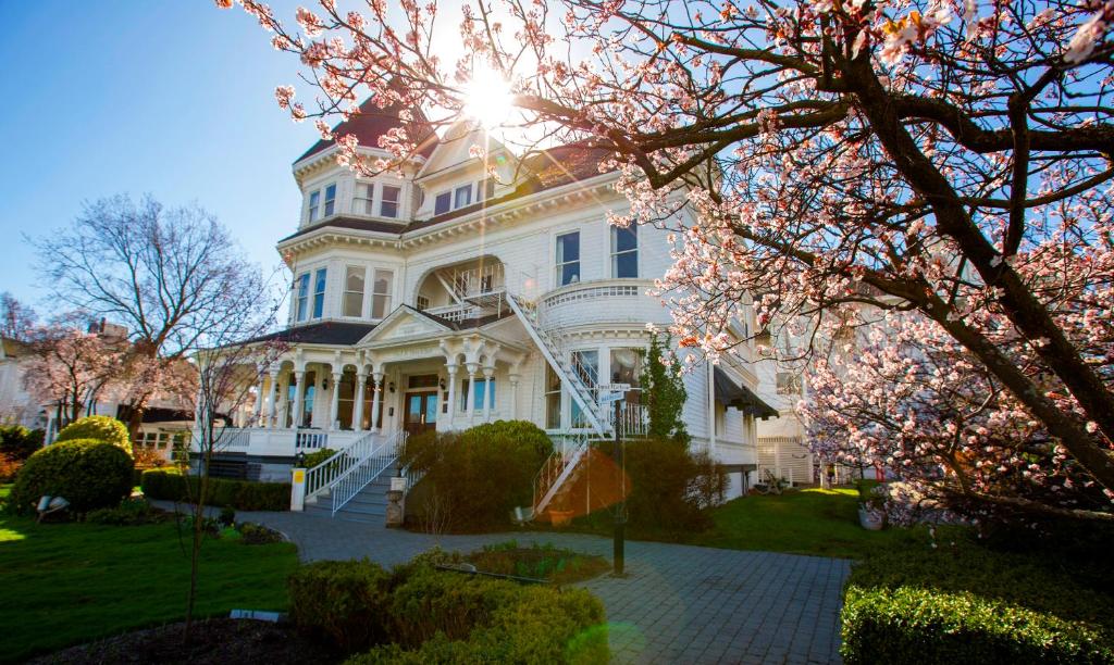 una gran casa blanca con el sol brillando en ella en Pendray Inn and Tea House, en Victoria