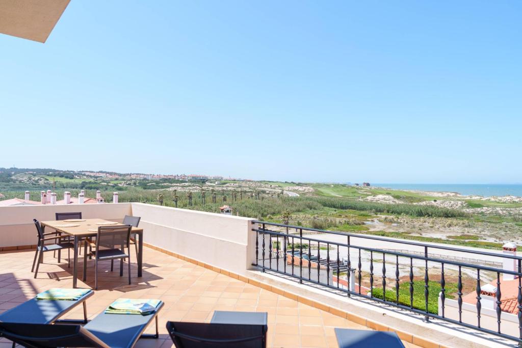 einen Balkon mit Tischen und Stühlen und Meerblick in der Unterkunft T3 Praia del Rey, piscina e vista mar, Óbidos, A7 in Óbidos
