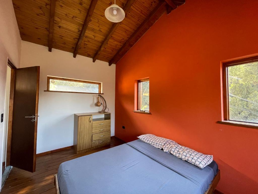 Un dormitorio con una pared de color naranja y una cama en Ventanas al Nahuel Huapi, en San Carlos de Bariloche